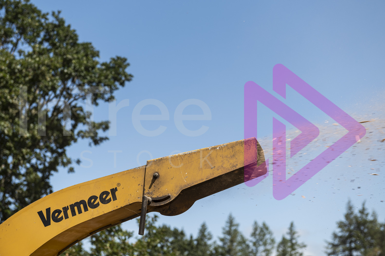 Close up of yellow chipper chute blowing out woodchip