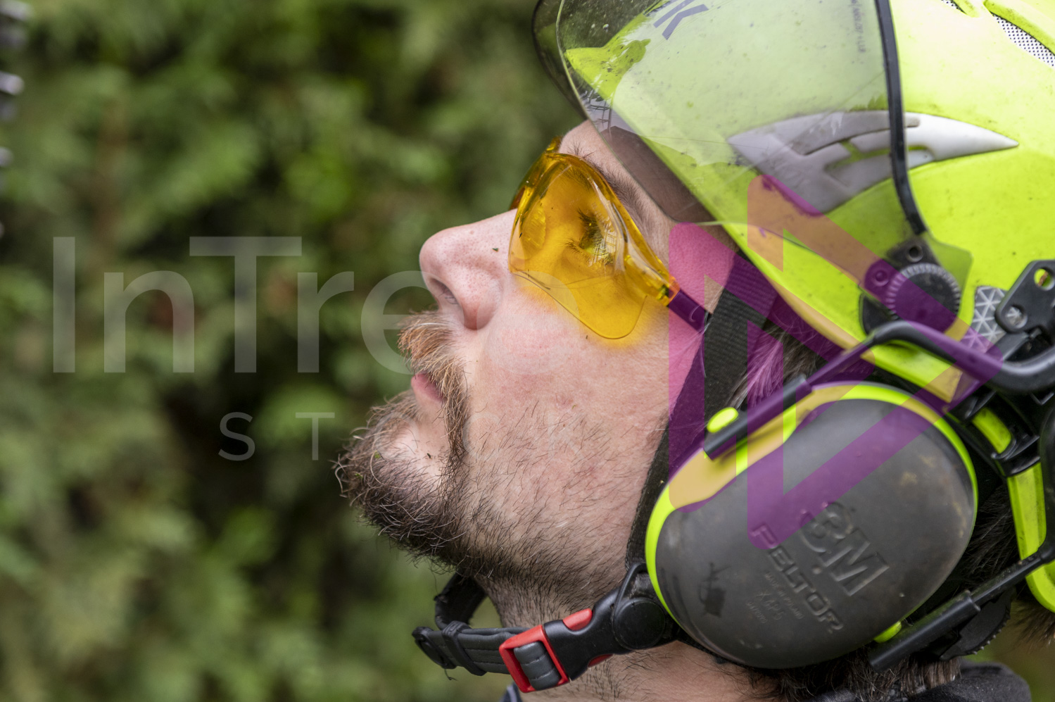 Close up of man wearing yellow safety glasses and a hi-viz green helmet with ear protection