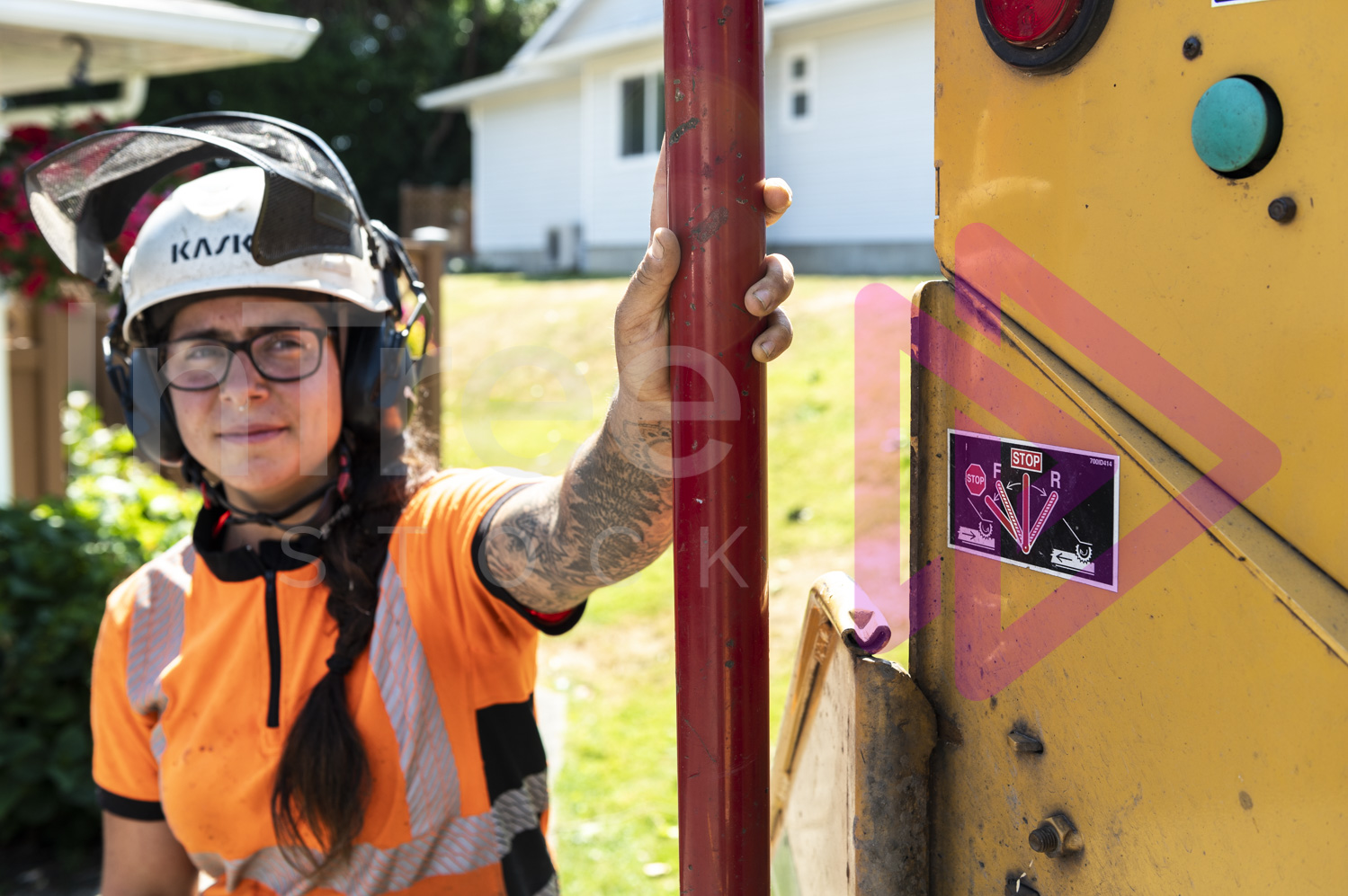 Female arborist pushing red stop bar with her hand on chipper