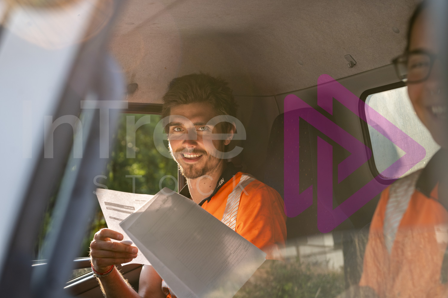 Man and woman in truck cab holding job sheets and smiling