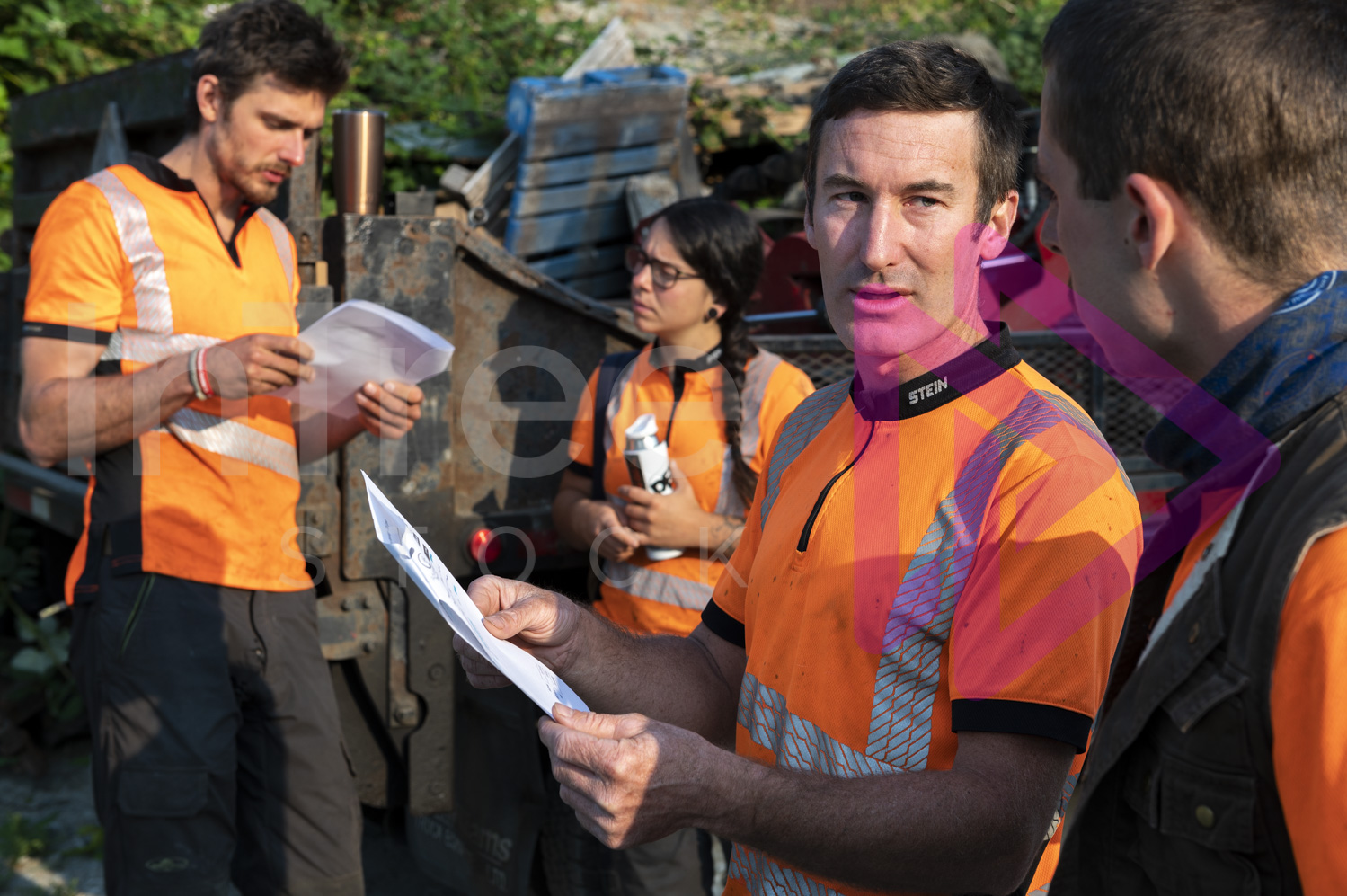 Man holding job sheet talking with crew all wearing hi-viz