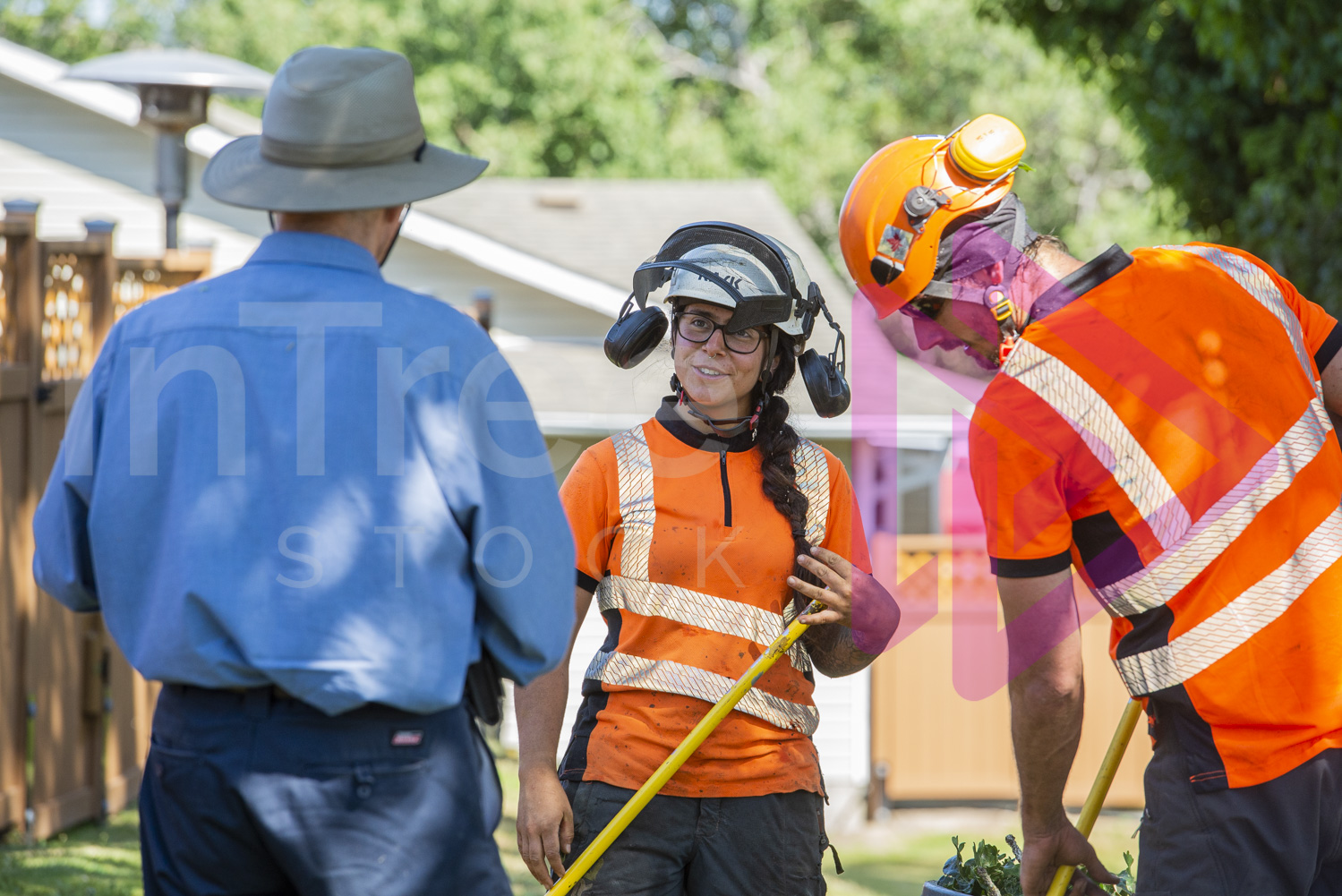 Man in blue shirt talking with female arborist holding rake