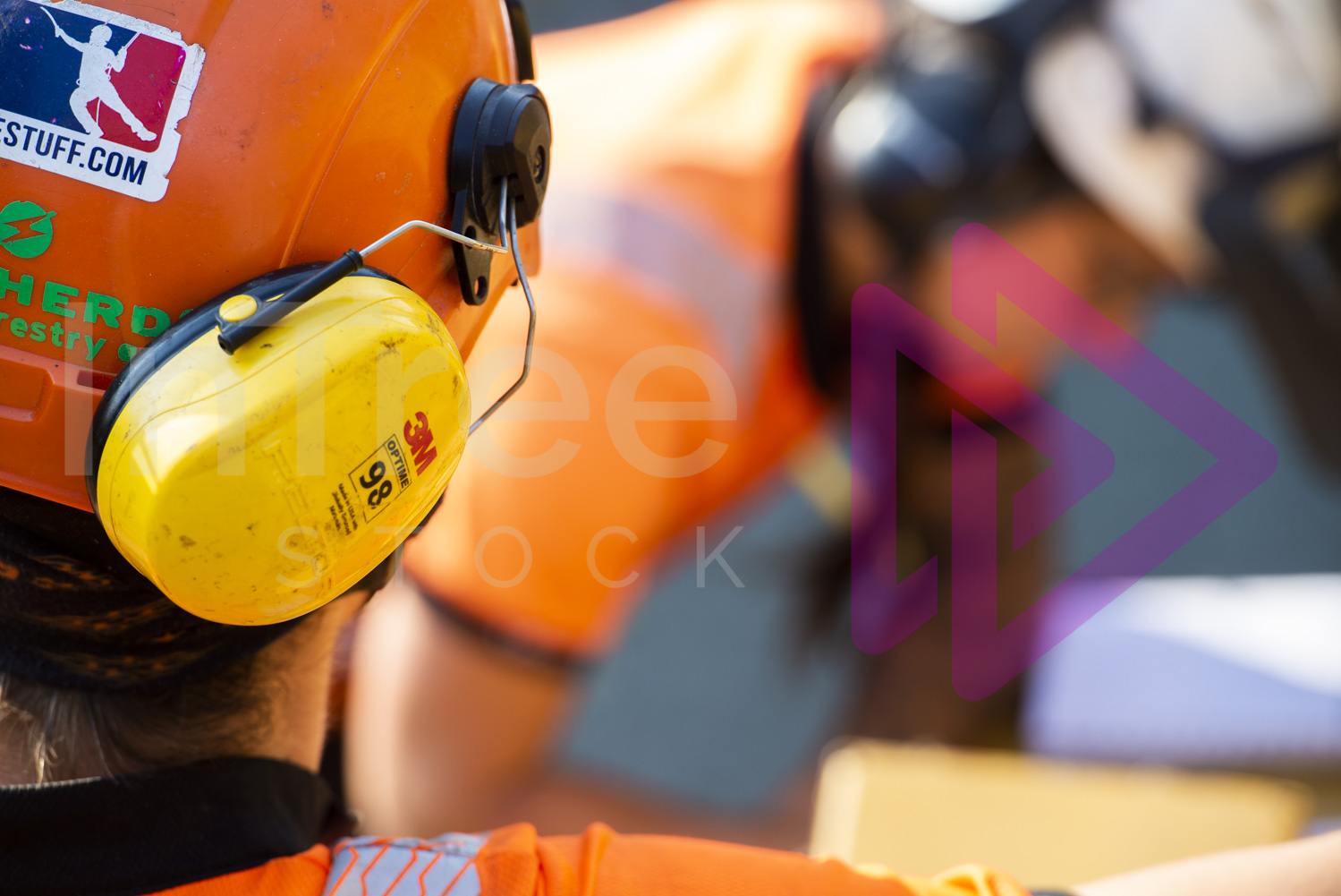 Yellow 3M Ear defender on helmet with woman blurred in background