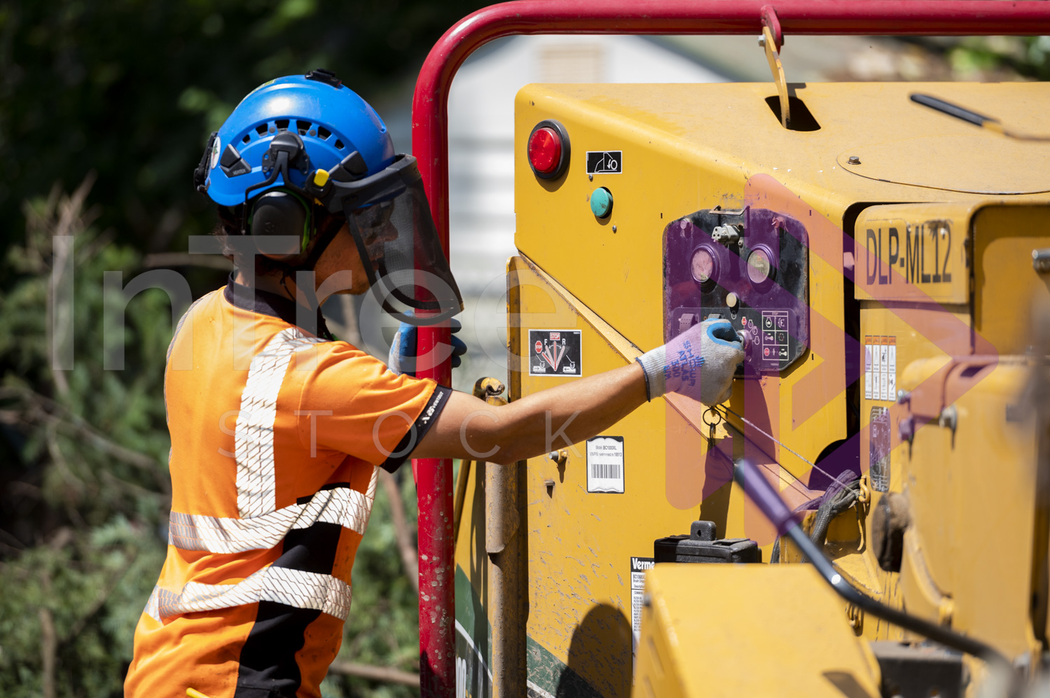 Man wearing blue helmet turning wood chipper on