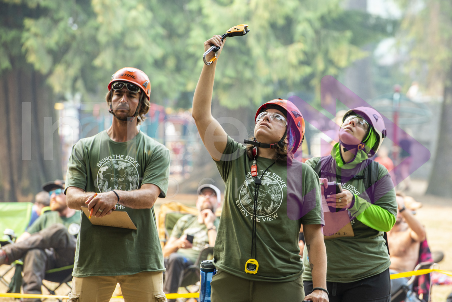 Female arborist holding up an item of climbing gear