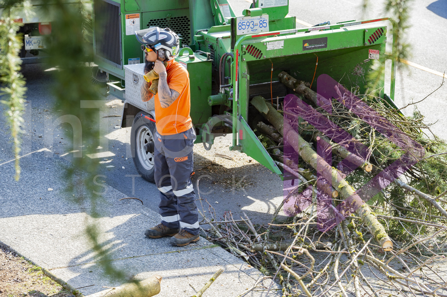 Man wearing helmet standing next to wood chipper