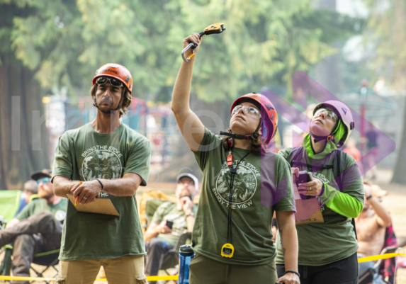 Female arborist holding up an item of climbing gear