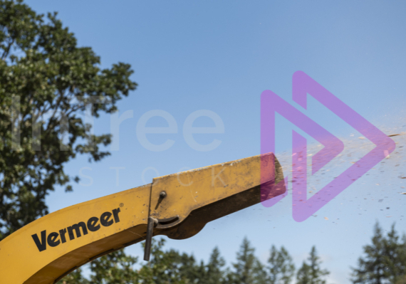 Close up of yellow chipper chute blowing out woodchip