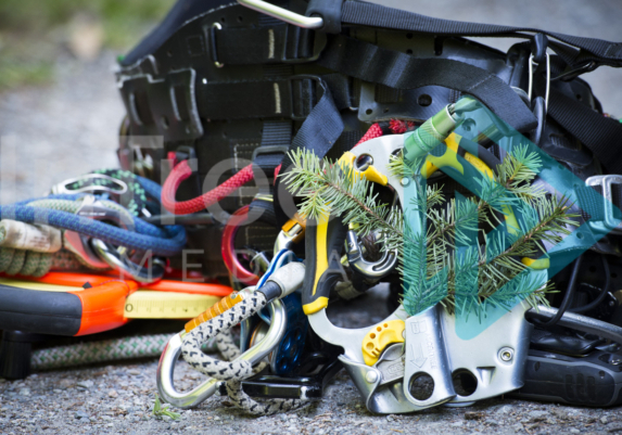 Climbing harness laying on the ground with double hand ascender and measure tape