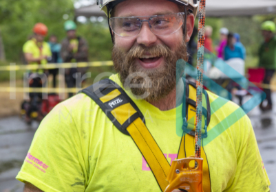 Excited arborist connected and ready for open ascent Male climbing arborist with big smile on his face ready to climb a rope