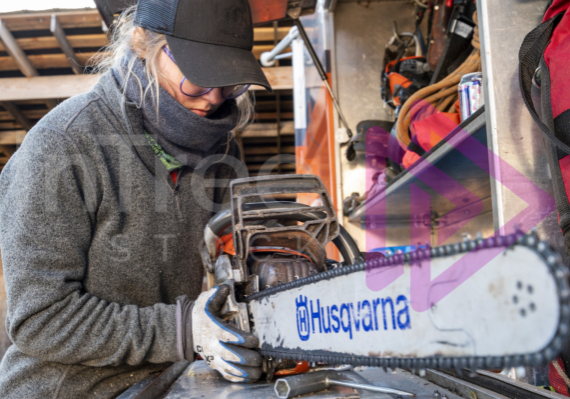 Woman with chainsaw on chip truck, hands with gloves on changing chain