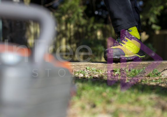 Green chainsaw protective boots in sunlight