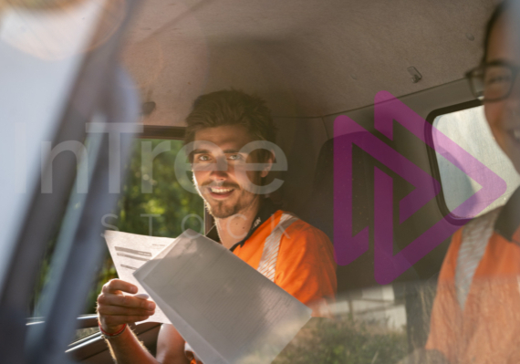 Man and woman in truck cab holding job sheets and smiling - Arborist Stock Photo-001-21-3476 Man and woman in truck cab holding job sheets and smiling