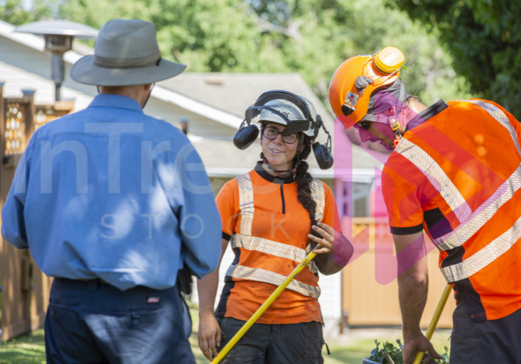 Man in blue shirt talking with female arborist holding rake - Arborist Stock photo-001-21-6153-1 Man in blue shirt talking with female arborist holding rake