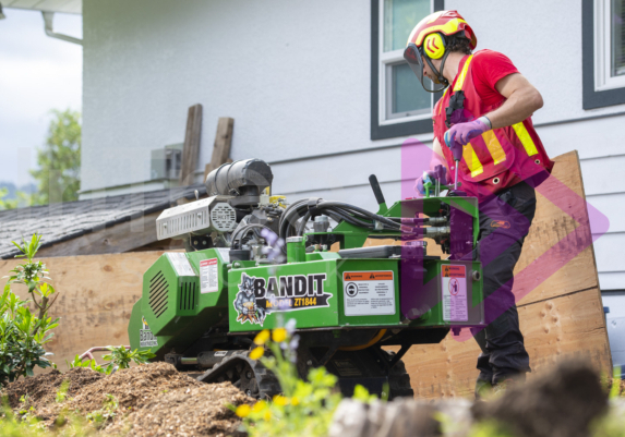 Man-in-hi-viz-using-stump-grinder- Man in hi-viz operating a green stump grinder