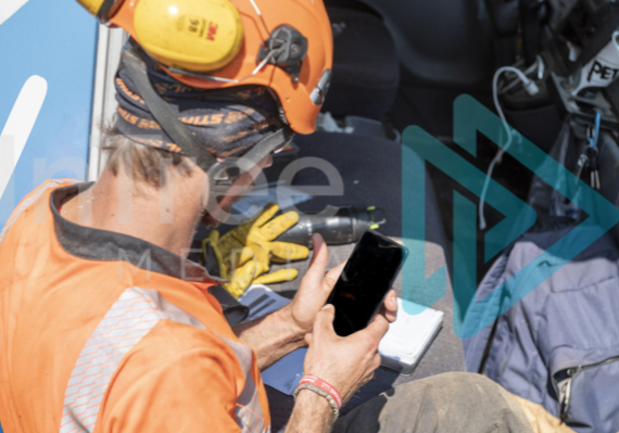 Male Arborist in high-vis using smart phone next to truck