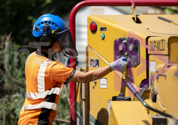 Man wearing blue helmet turning wood chipper on Man wearing blue helmet turning wood chipper on