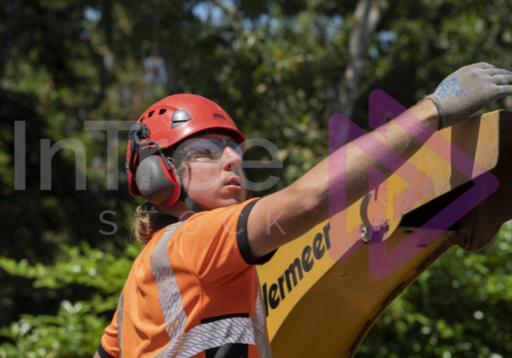 Man wearing red helmet adjusting chipper chute Man wearing red helmet adjusting chipper chute