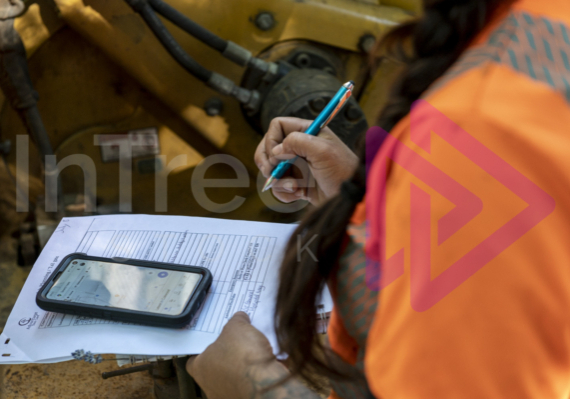 Pre-work-site-safety-check Female holding pen filling out form with smart phone