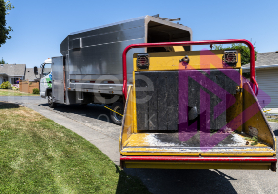 Yellow chipper and chip truck parked on residential driveway on a sunny day