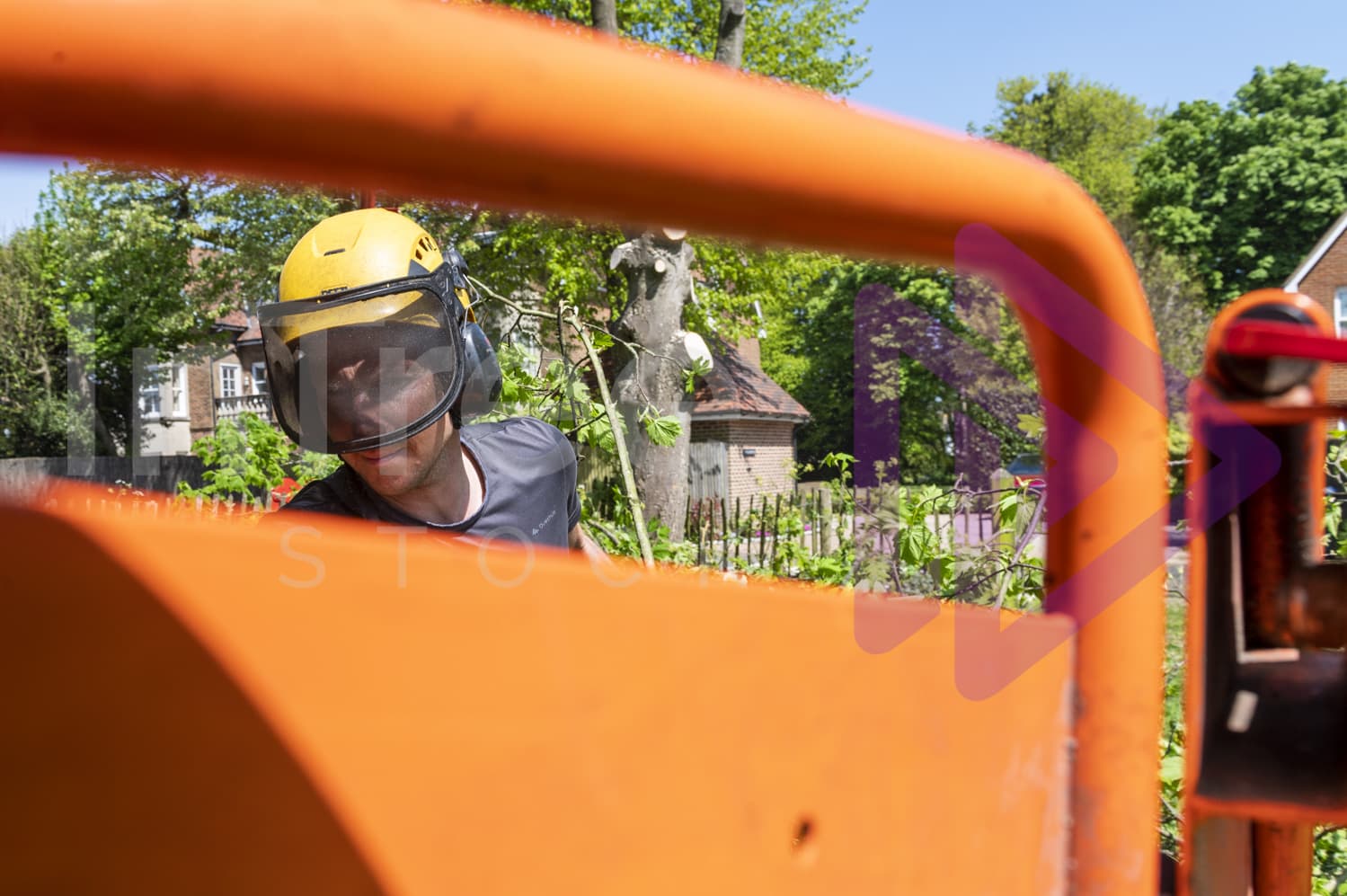 Man in yellow helmet with visor feeding wood chipper