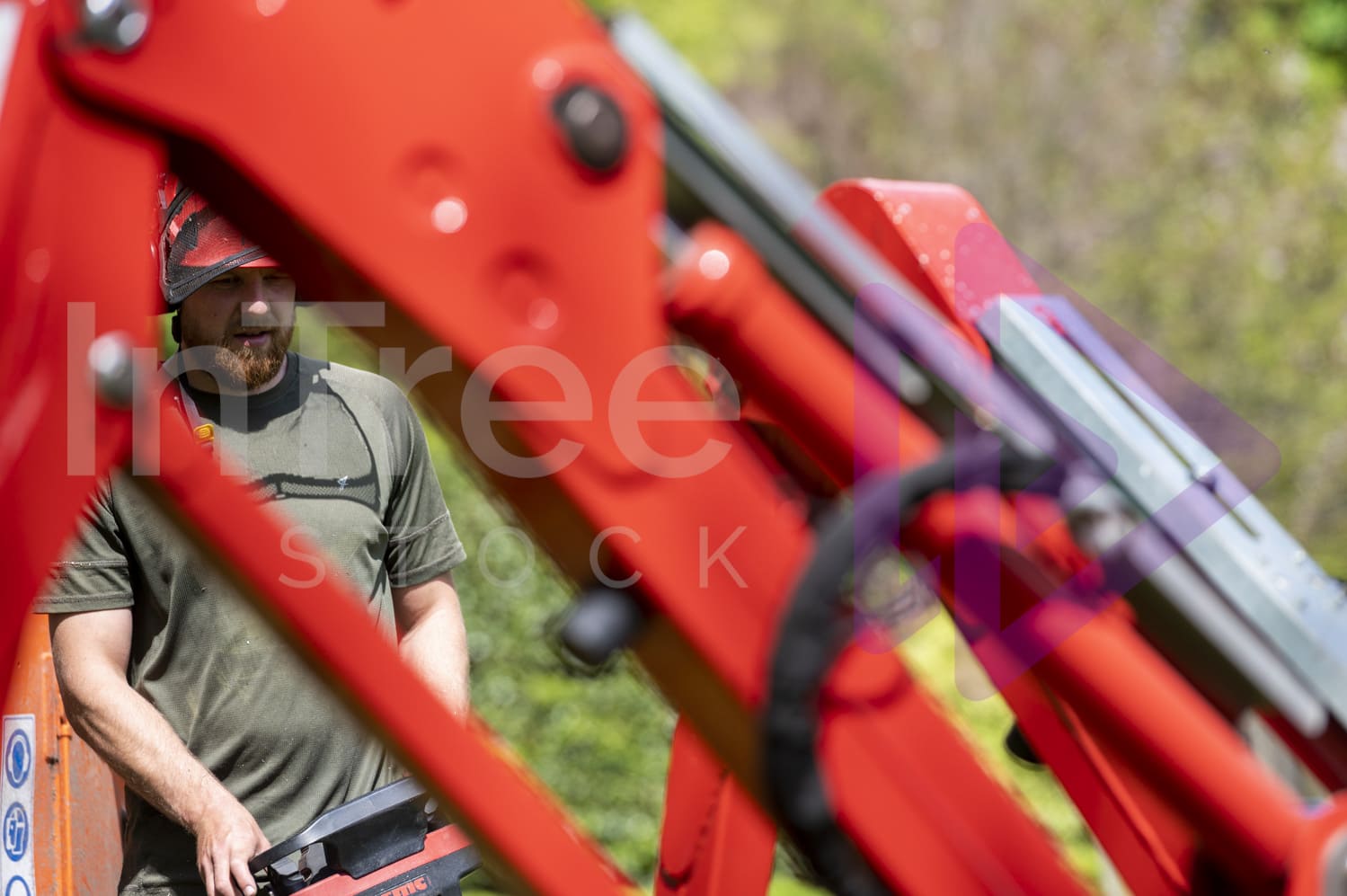 Looking through spider lift legs to man extending outriggers with remote control